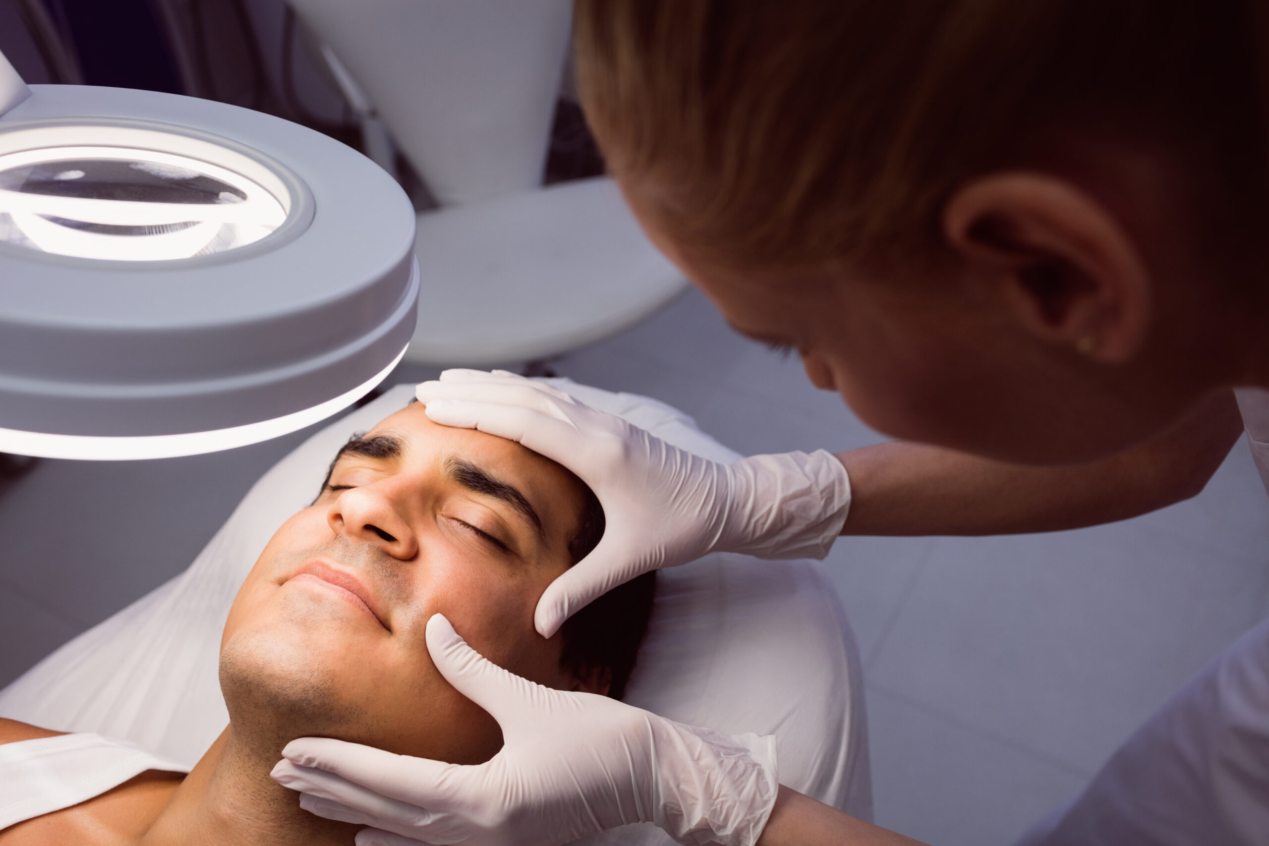 Doctor examining mans face for cosmetic treatment at clinic